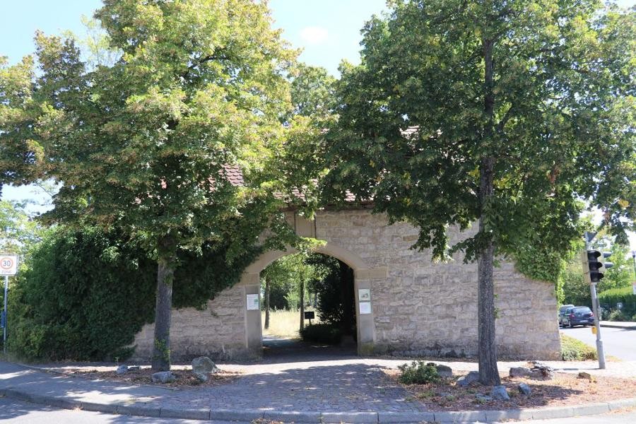 Blick auf das mit zwei Bäumen eingesäumte Torhaus des Rutesheimer Friedhofs.