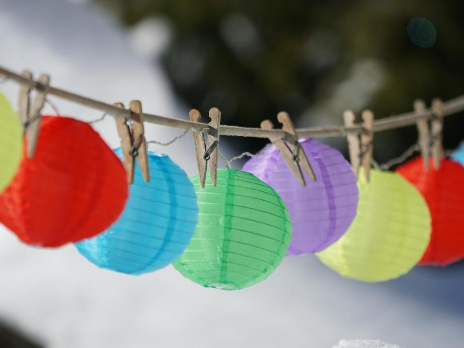 Lampions_pixabay An einer Schnur hängen bunte Papierlampions, die mit Holzwäscheklammern befestigt sind.