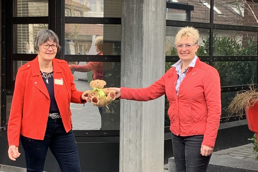 Monika Friedrich und Bürgermeisterin Susanne Widmaier stehen vor dem Neuen Rathaus und halten gemeinsam den kleinen Teddybären in der Hand, der um den Hals die grüne Schleife mit der Aufschrift Tag der Kinderhospizarbeit trägt.     