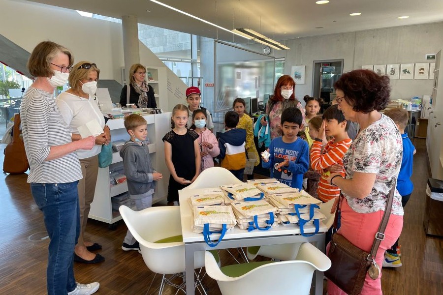 Kinder und Betreuerinnen der Sprachförderung sowie Büchereileiterin Hagemeier-Beck bei der Verteilung der Geschenk-Taschen.          