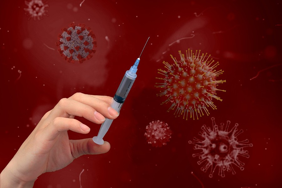 Rote Corona-Viren im Hintergrund und eine Hand mit Spritze im Vordergrund