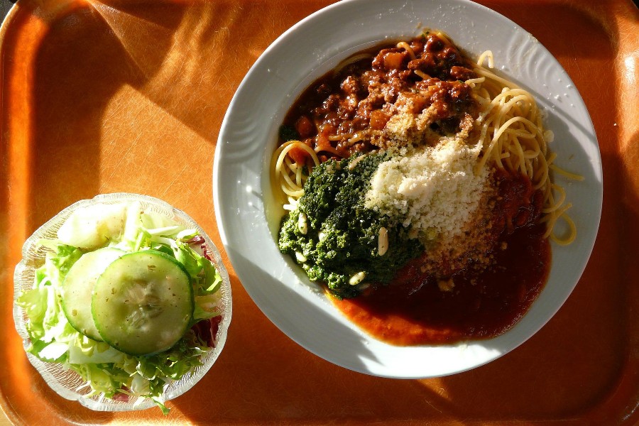 Tablett mit weißem Teller mit Spaghetti, Tomatensauce, Parmesan und eine kleines Teller mit grünem Salat.                          