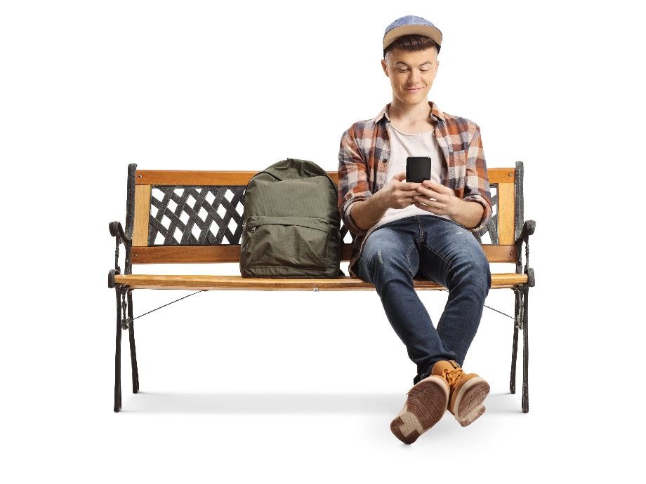 Ein junger Mann sitzt auf einer Holzbank, neben sich einen grünen Rucksack und wartet auf eine Mitfahrgelegenheit.                    