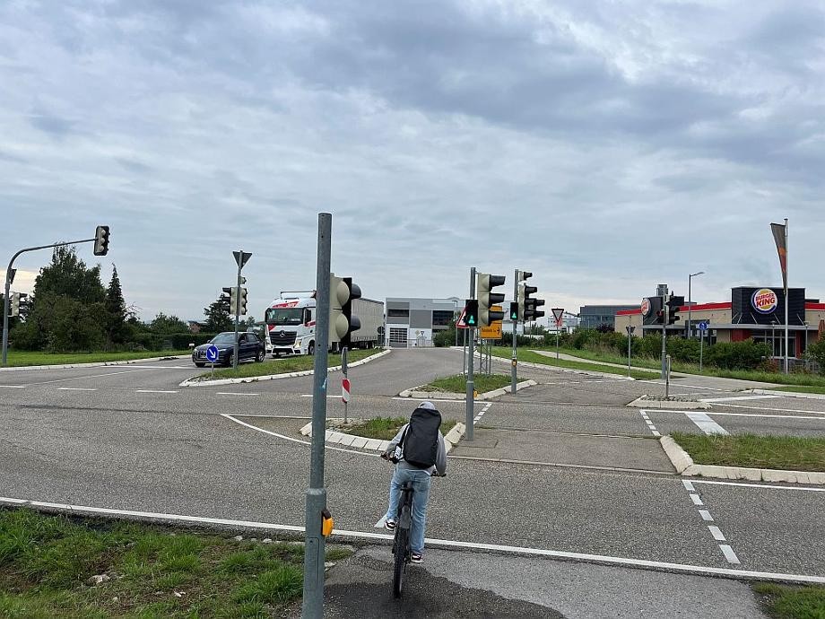 Blick auf die Kreuzung mit Ampelanlagen, einem Auto und einem Radfahrer.