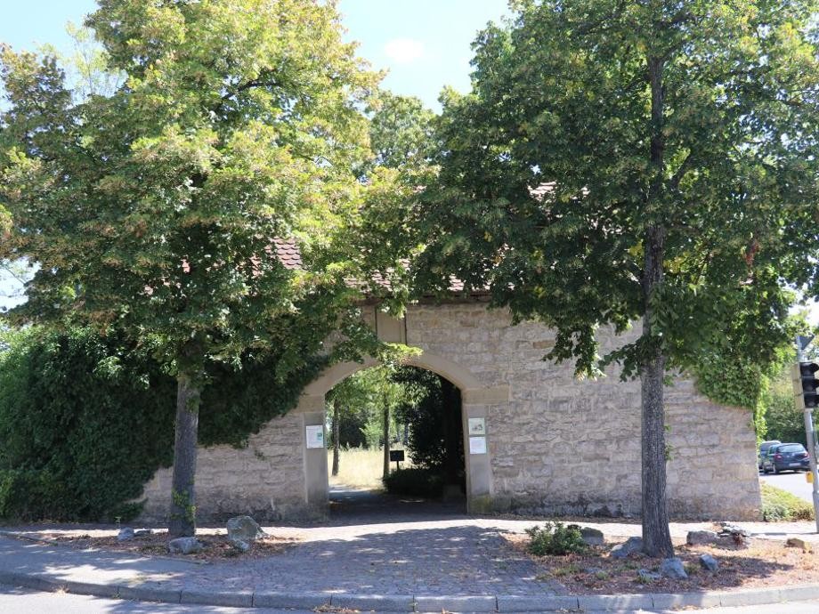 Blick auf das mit zwei Bäumen eingesäumte Torhaus des Rutesheimer Friedhofs.