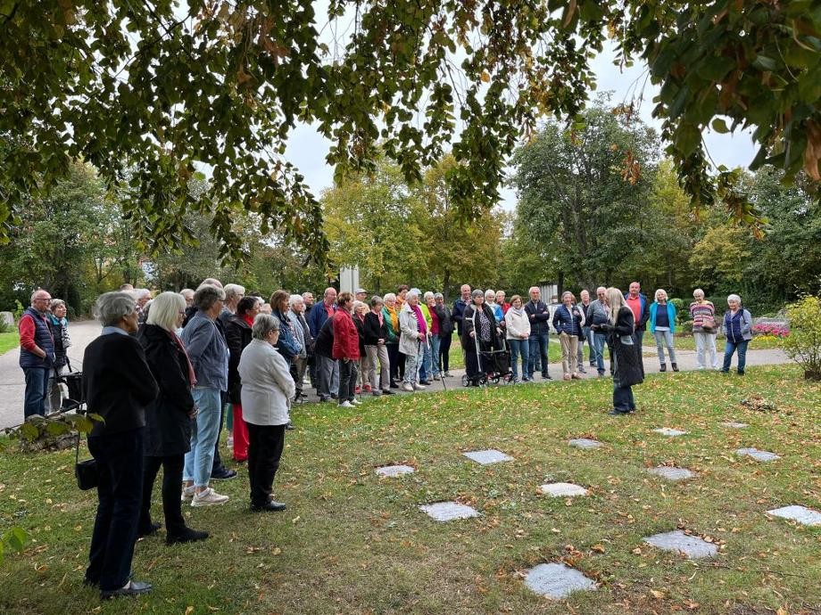 Eine Personengruppe besichtigt auf dem Rutesheimer Friedhof ein Urnengrabfeld.