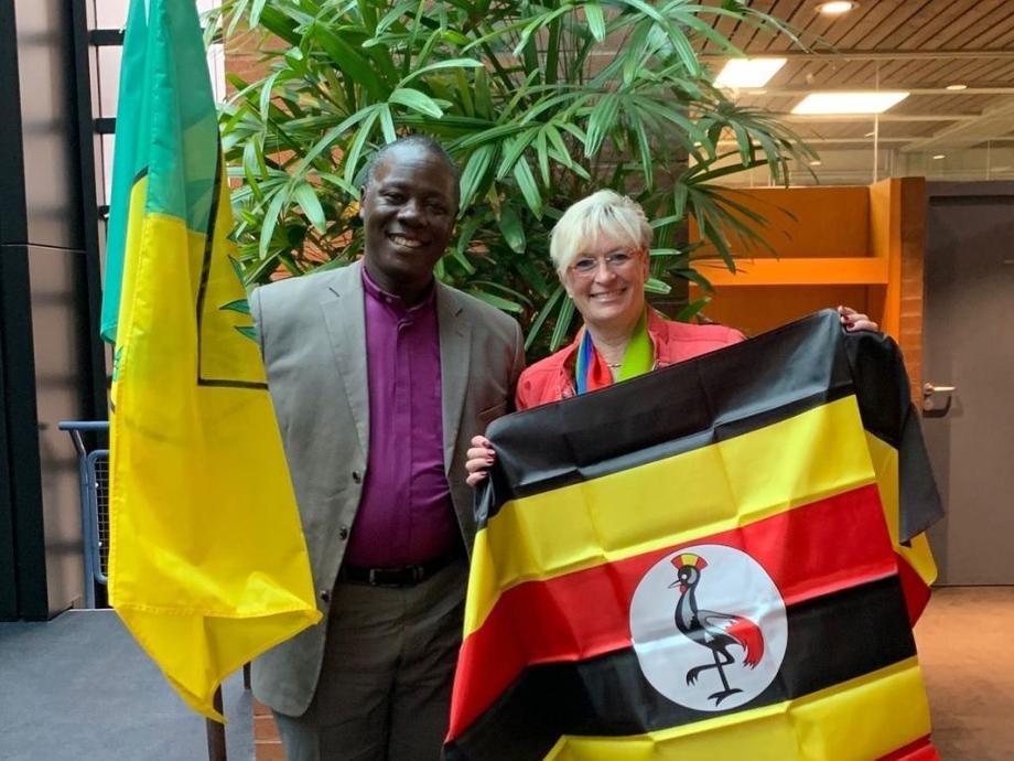 Bürgermeisterin Widmaier und Bischof Kijjambu aus Uganda halten die farbigen Flaggen des jeweils anderen in den Händen.