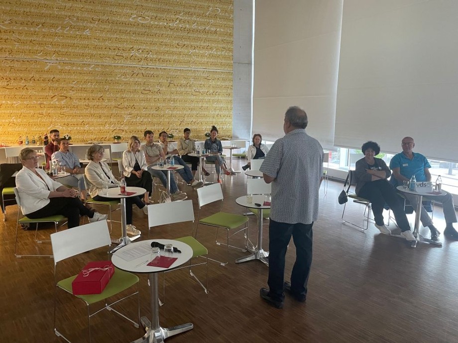 Unternehmensvesper im Bürgersaal Mehrere Personen sitzen im Halbkreis vor dem Referenten Thomas Römer und hören seinem Vortrag zu.