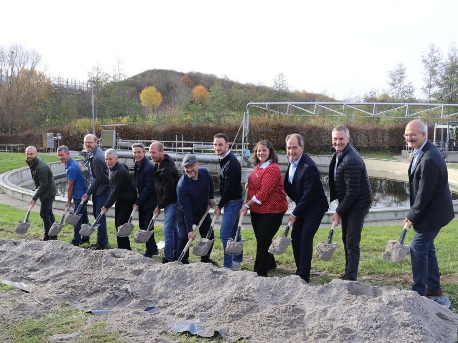 Spatenstich Kläranlage Rutesheim Mehrere Personen stehen mit ihren Spaten zwischen einem kleinen Sandhügel und einem Klärschlammbecken.