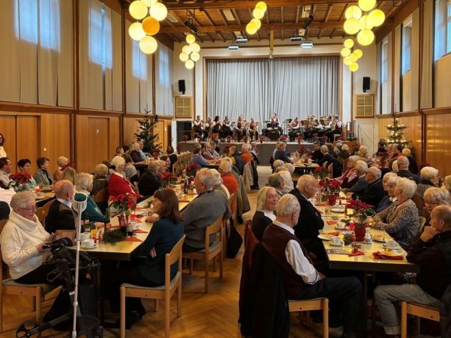 Senioren-Weihnachtsnachmittag 2025 In der weihnachtlich geschmückten Festhalle sitzen viele Personen an Tischen, trinken Kaffee und essen Kuchen.