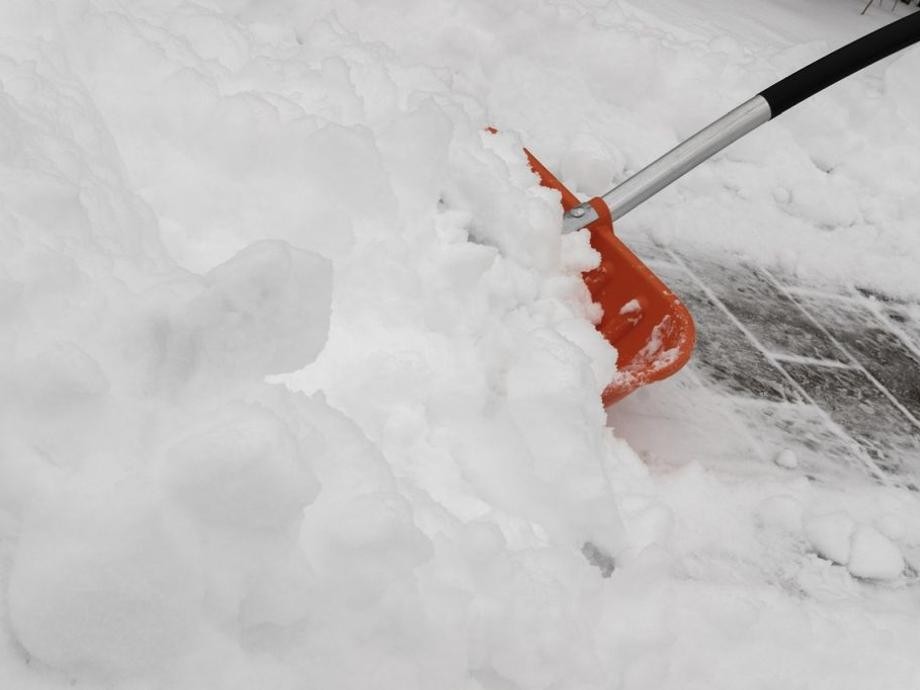 Schneeschaufel Eine rote Schneeschaufel mit schwarzem Griff im Schnee.