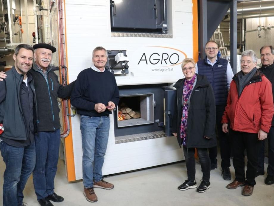 Inbetriebnahme Heizzentrale Gruppenbild mit sieben Personen am Ofen in der Heizzentrale.