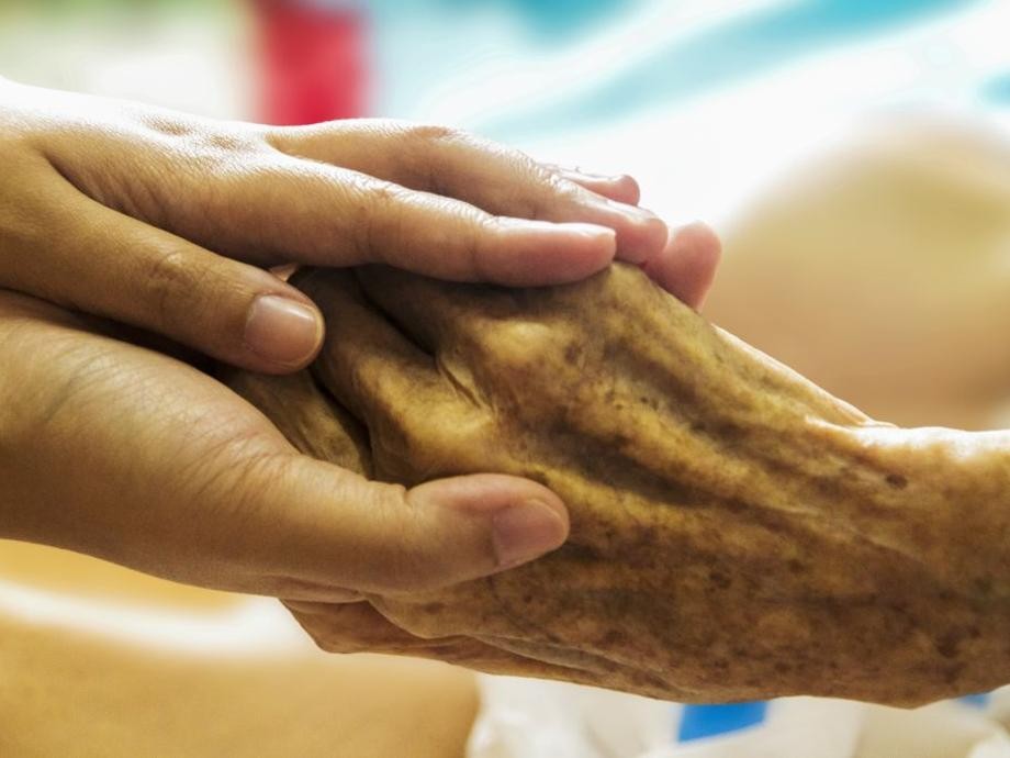 Hospiz_pixabay Die Hand einer jüngeren Person hält die Hand einer älteren im Sterben liegenden Person.