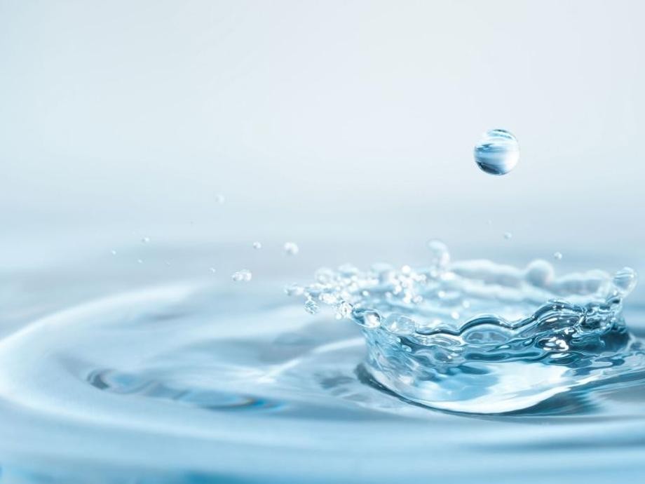 Wassersparen Mehrere Wassertropfen spritzen ins Wasser und bilden Wasserkreise.