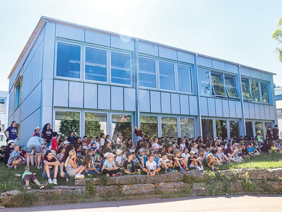 Stara 2026 Viele Kinder der Stara vor stehen oder sitzen vor einem Gebäude der Schule.