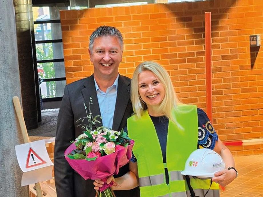 Dienstantritt Stadtbaumeisterin Larissa Grau Bürgermeisterin Tobias Pokrop und Stadtbaumeisterin Larissa Grau mit einem Blumenstrauß und Bauhelm in der Hand.