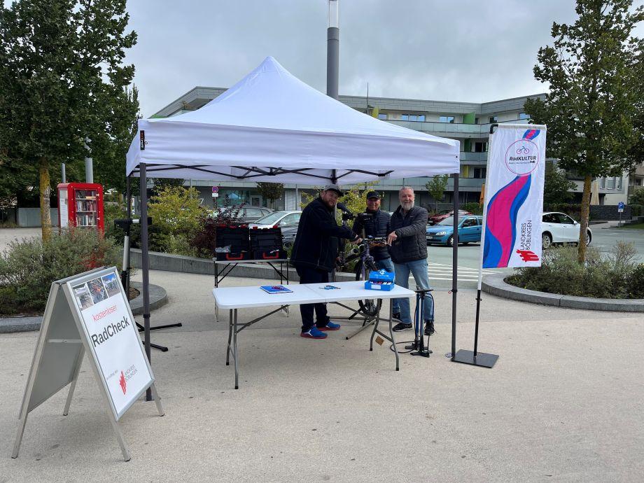 Drei Personen stehen unter einem weißen Pavillon an einem Tisch und führen den RadCHECK durch.
