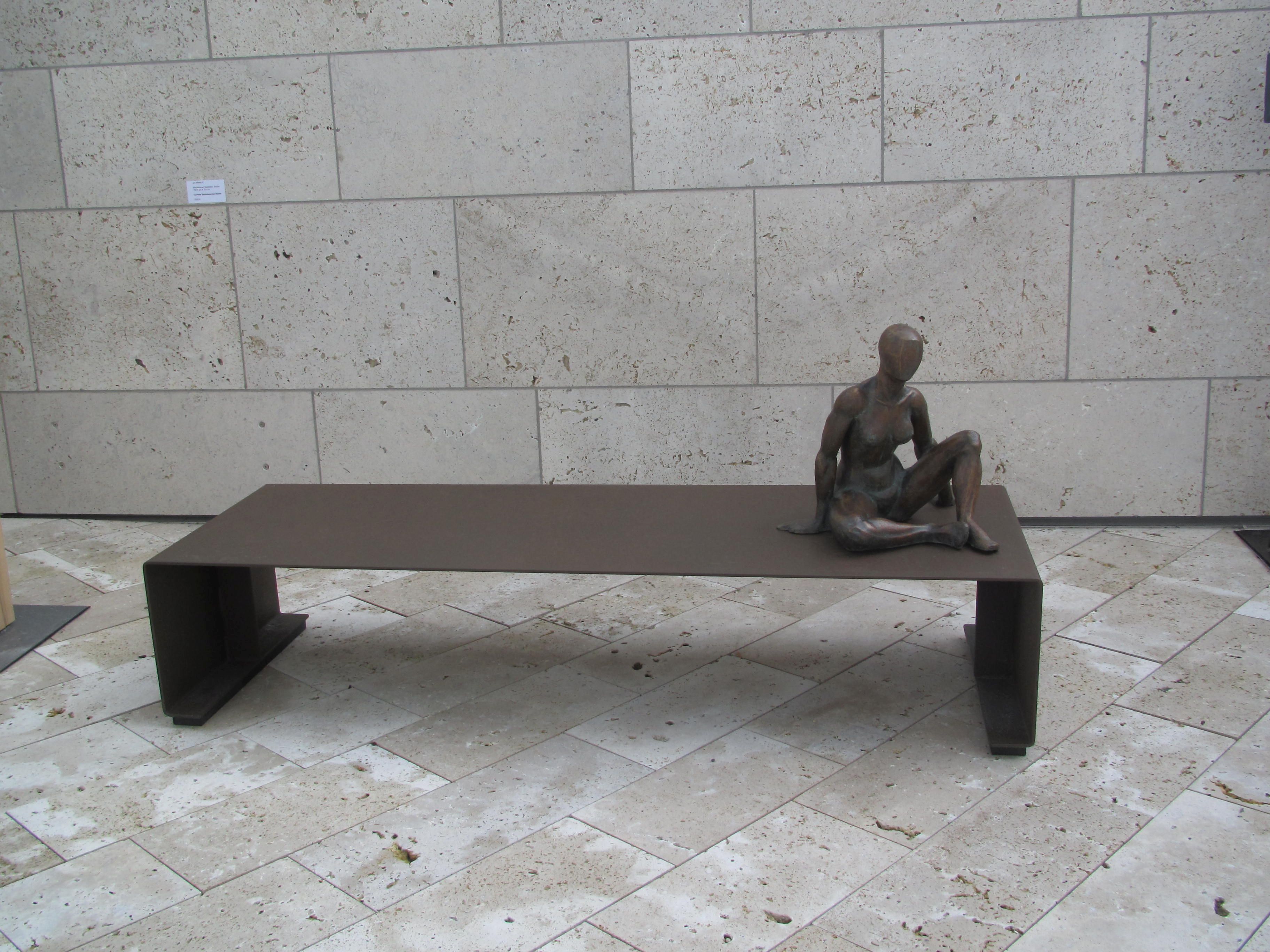 Kunstobjekt von Corinna Beutelspacher-Stehle: länglicher Tisch mit einer sitzenden weiblichen Skulptur                   
