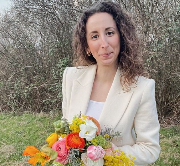 Frau Schumaeker hält einen bunten Frühlingsstrauß in den Händen.