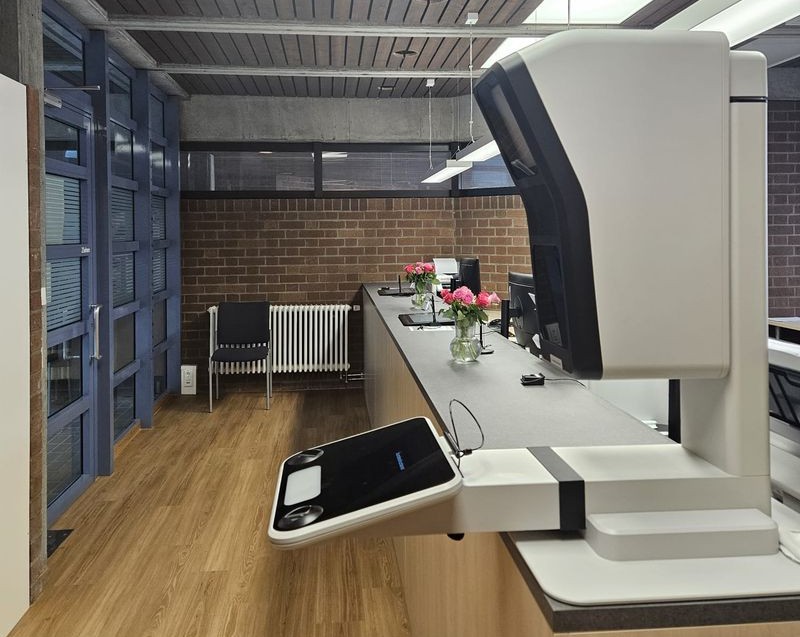 Bürgeramt mit langer Theke, Arbeitsplätzen und dem neuen Terminal für Passbilder.                     