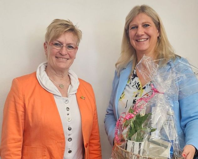 Bürgermeisterin Melanie Hettmer übergibt Bürgermeisterin Susanne Widmaier einen in Folie verpackten Geschenkkorb.