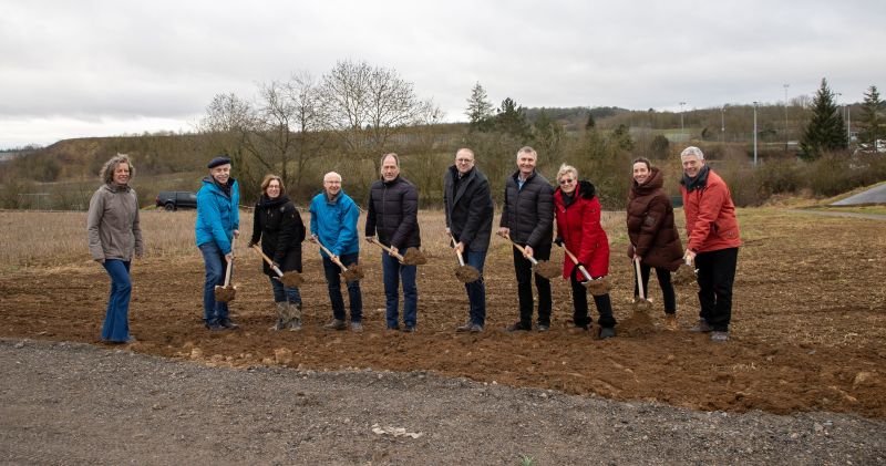 Gruppenbild mit mehreren Personen, die Spaten mit Erde in den Händen halten.