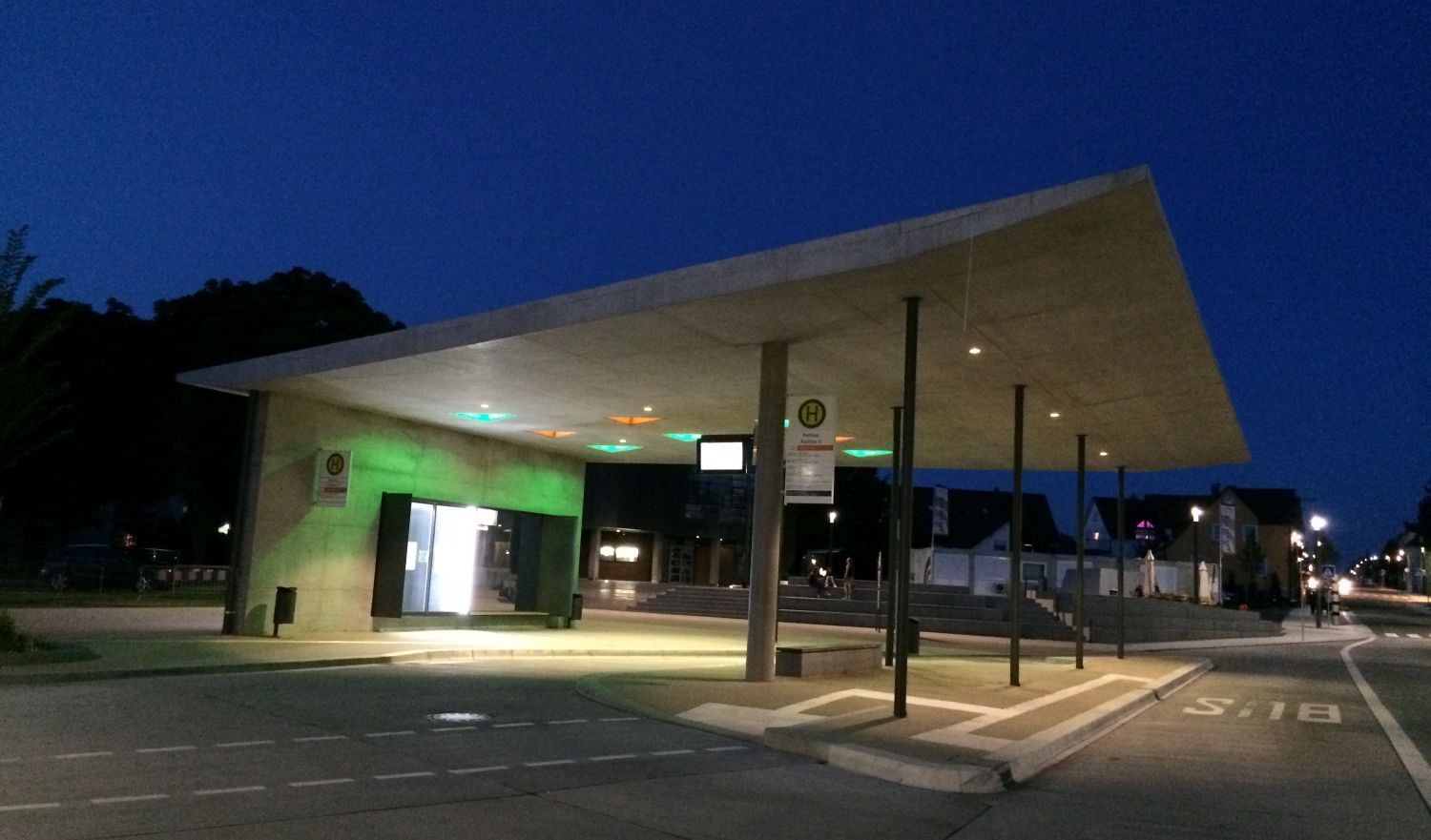 Blick auf die moderne Haltestelle Rathaus mit Beton und grünem Glas.