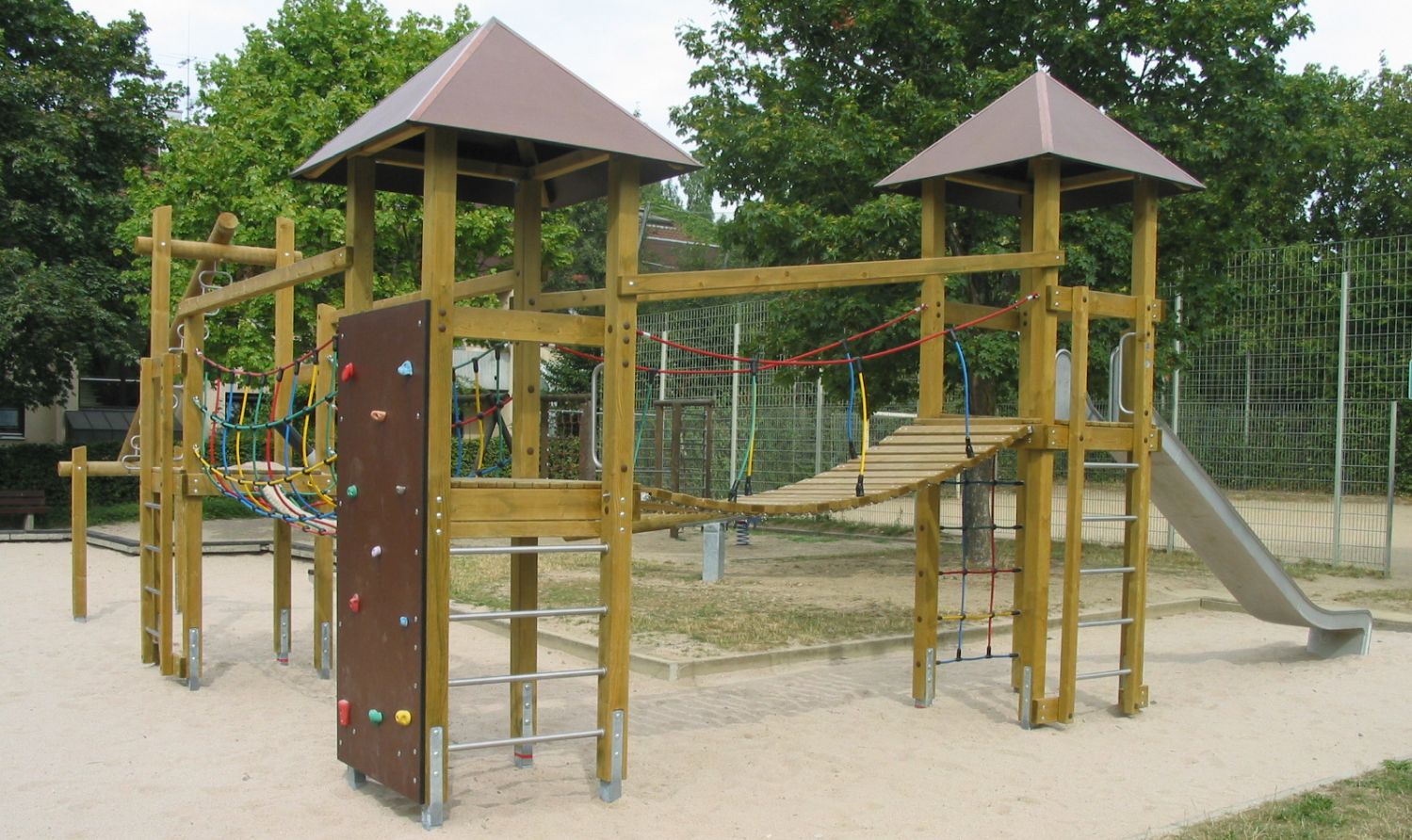 Zu sehen ist ein Klettergerüst aus Holz mit Metallrutsche am Spielplatz Scheibbser Straße