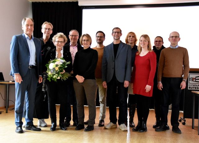 Gruppenbild mehrerer Personen, Frau Hemminger mit Blumenstrauß.