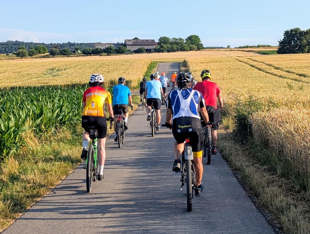 Eine Gruppe Radfahrer radeln auf einem geteerten Weg zwischen den Rutesheimer Feldern.