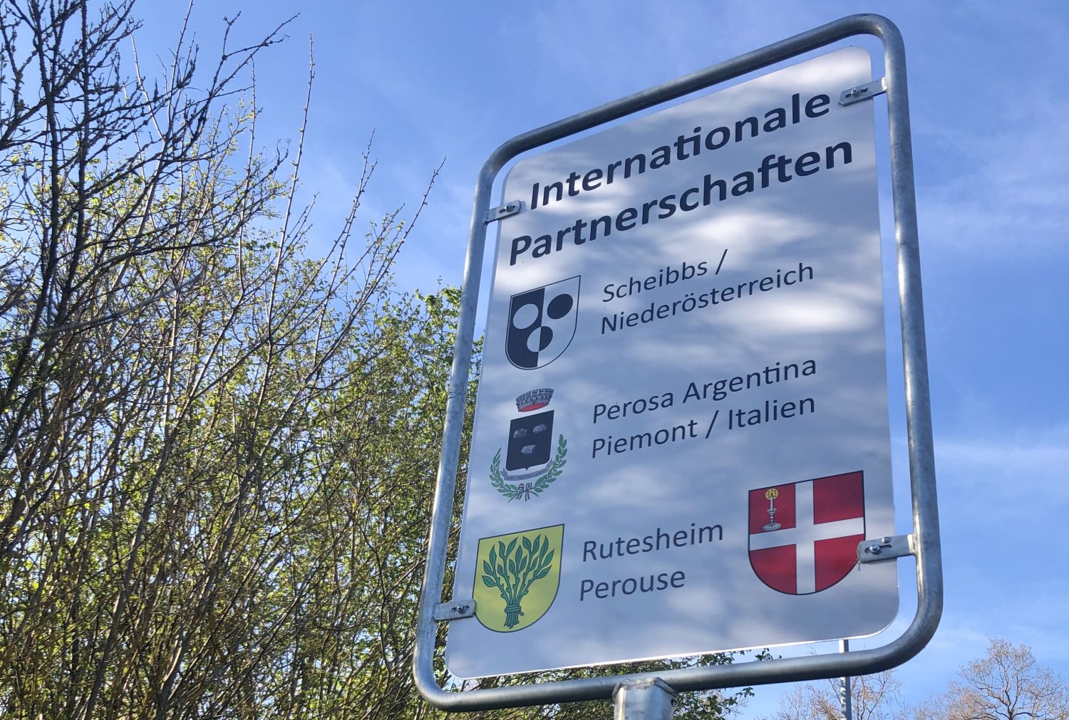 Straßenschild mit Aufschrift und den dazugehörigen Wappen: Internationale Partnerschaften Scheibbs Niederösterreich, Perosa Argentina Piemont/Italien,                 